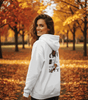Frau trägt weißen Lira Bequemer Hoodie im herbstlichen Park für urbanen Stil und Komfort