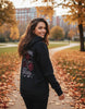 Frau trägt schwarzen Slim Fit Hoodie mit Premium Black Rose Design im herbstlichen Park